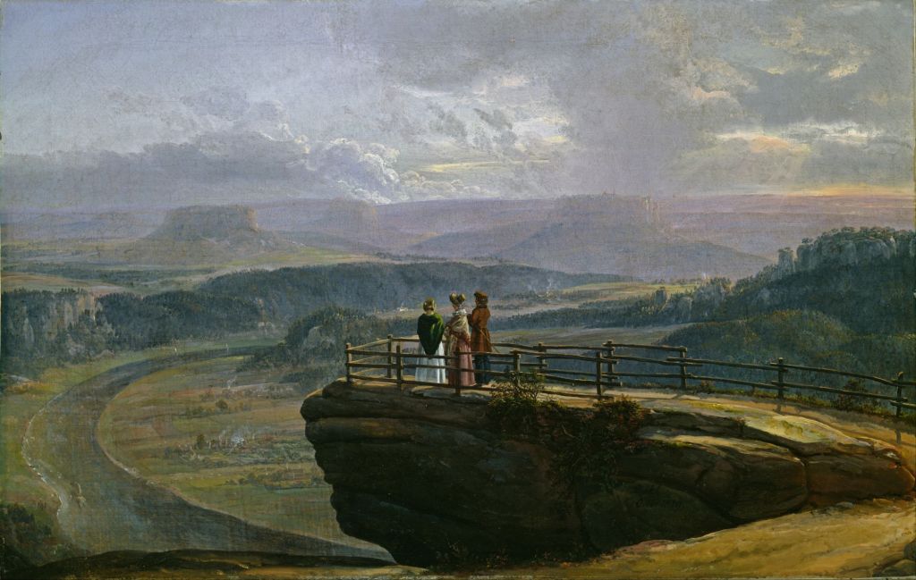 A couple stands on a rocky outcrop overlooking a vast landscape with rolling hills, a river, and a cloudy sky, showcasing nature's beauty.
